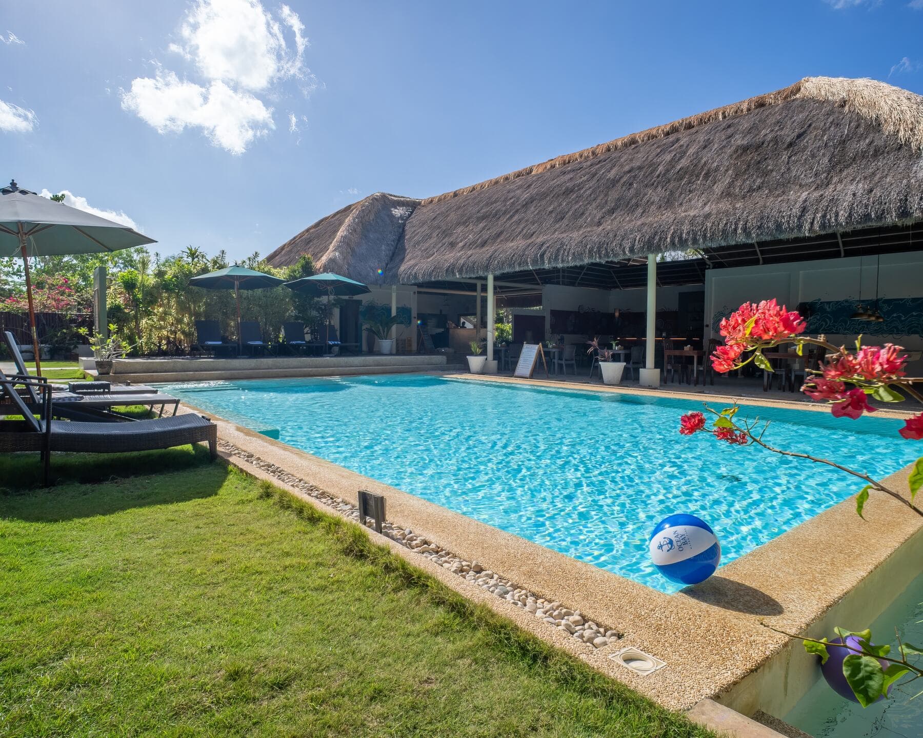 Pool, sun loungers, and thatched restaurant pavilion